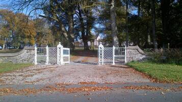 A gated entrance to a park with a stone wall and metal gate.