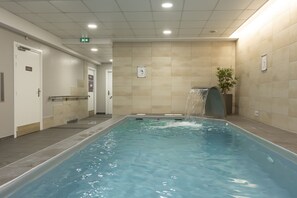 Uma piscina com um elemento aquático, paredes azulejadas e uma porta com um aviso.
