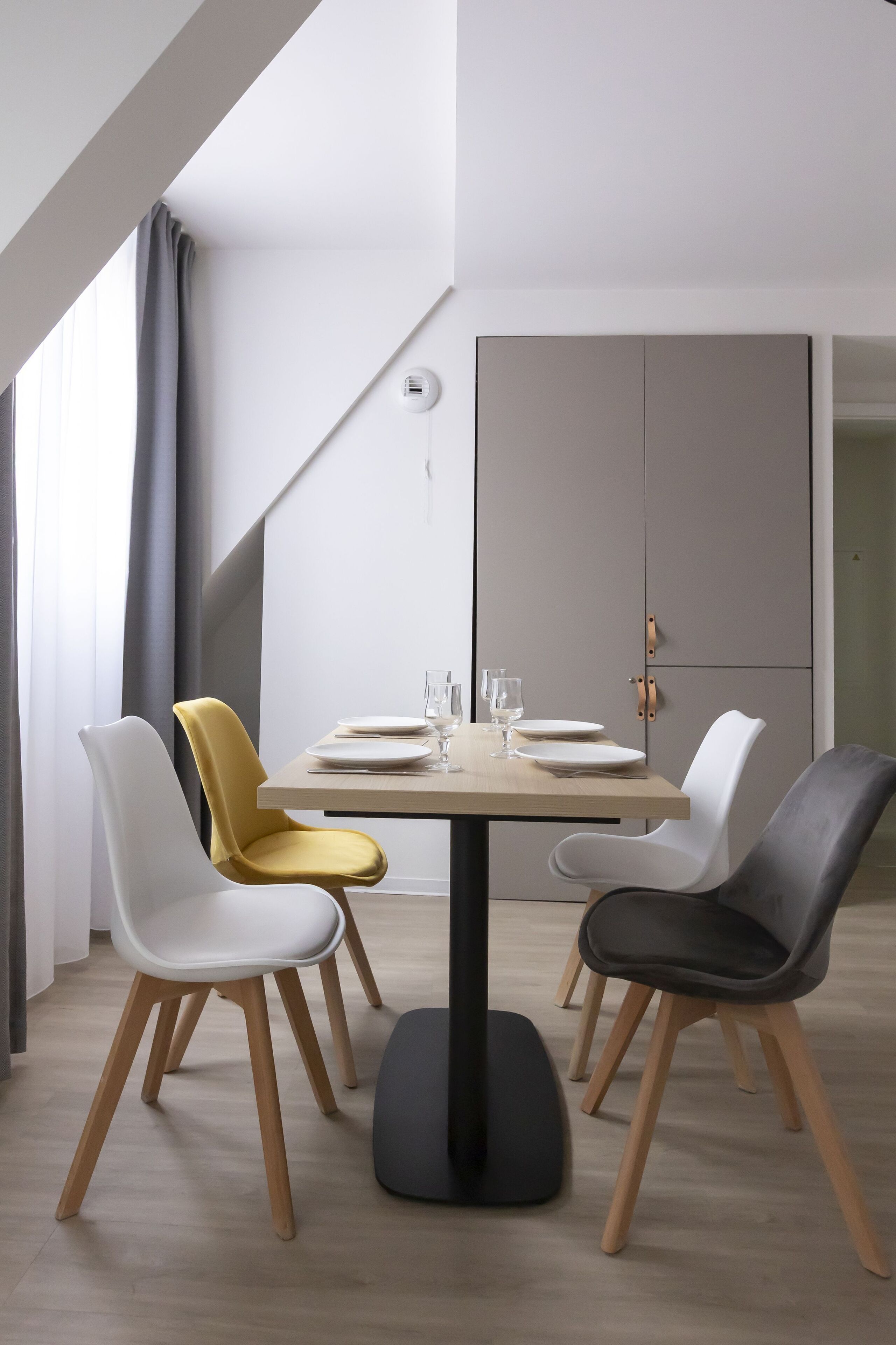 Un espace repas moderne avec une table ronde prévue pour quatre personnes, entourée de chaises aux pieds en bois.