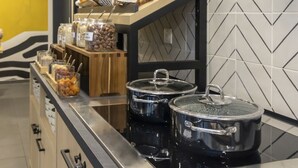 Un plan de travail de cuisine avec des bocaux remplis de nourriture, un panier de fruits et deux casseroles sur la cuisinière.