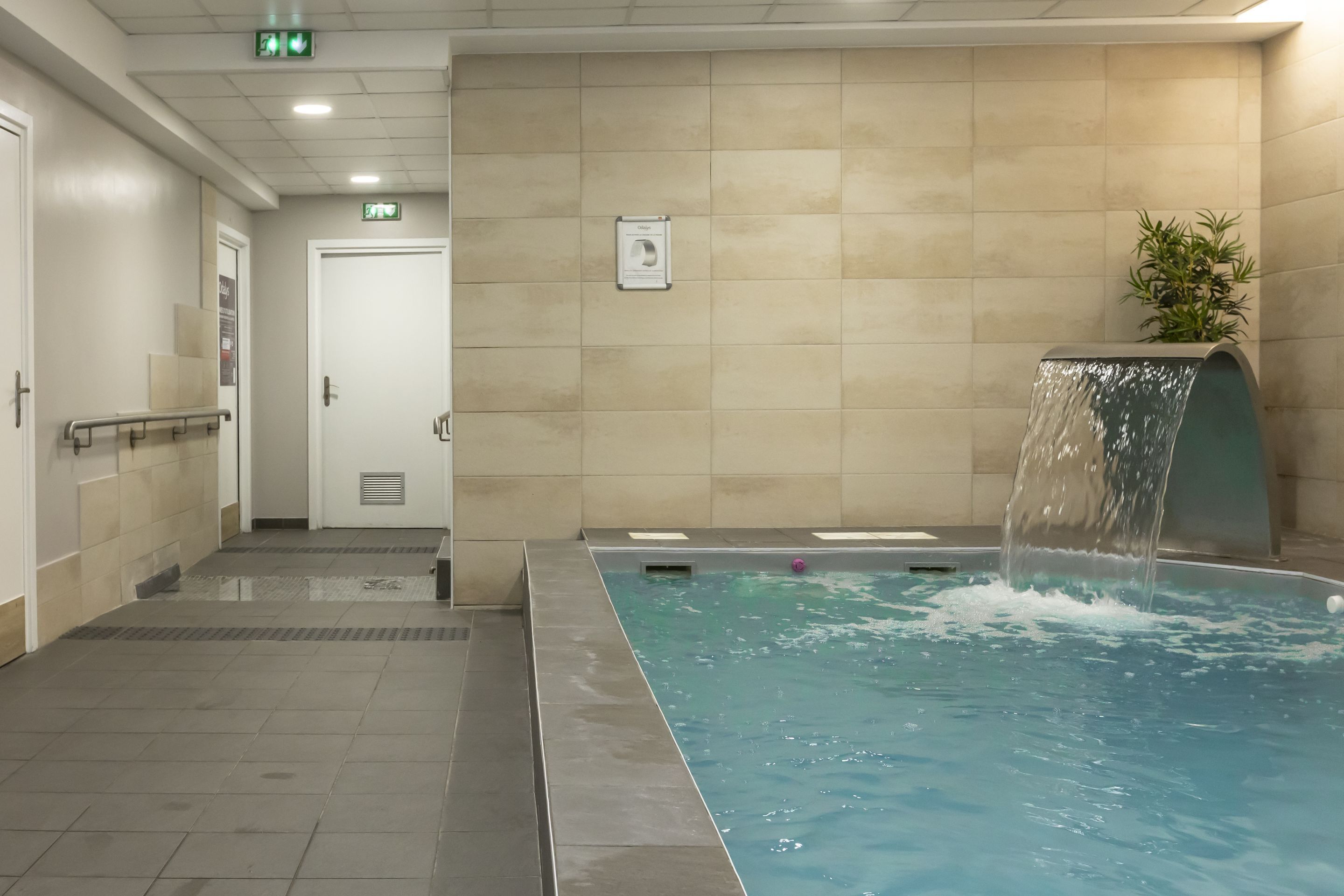 Une piscine agrémentée d’une cascade, une porte et un panneau fixé au mur.