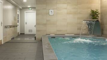 Une piscine agrémentée d’une cascade, une porte et un panneau fixé au mur.