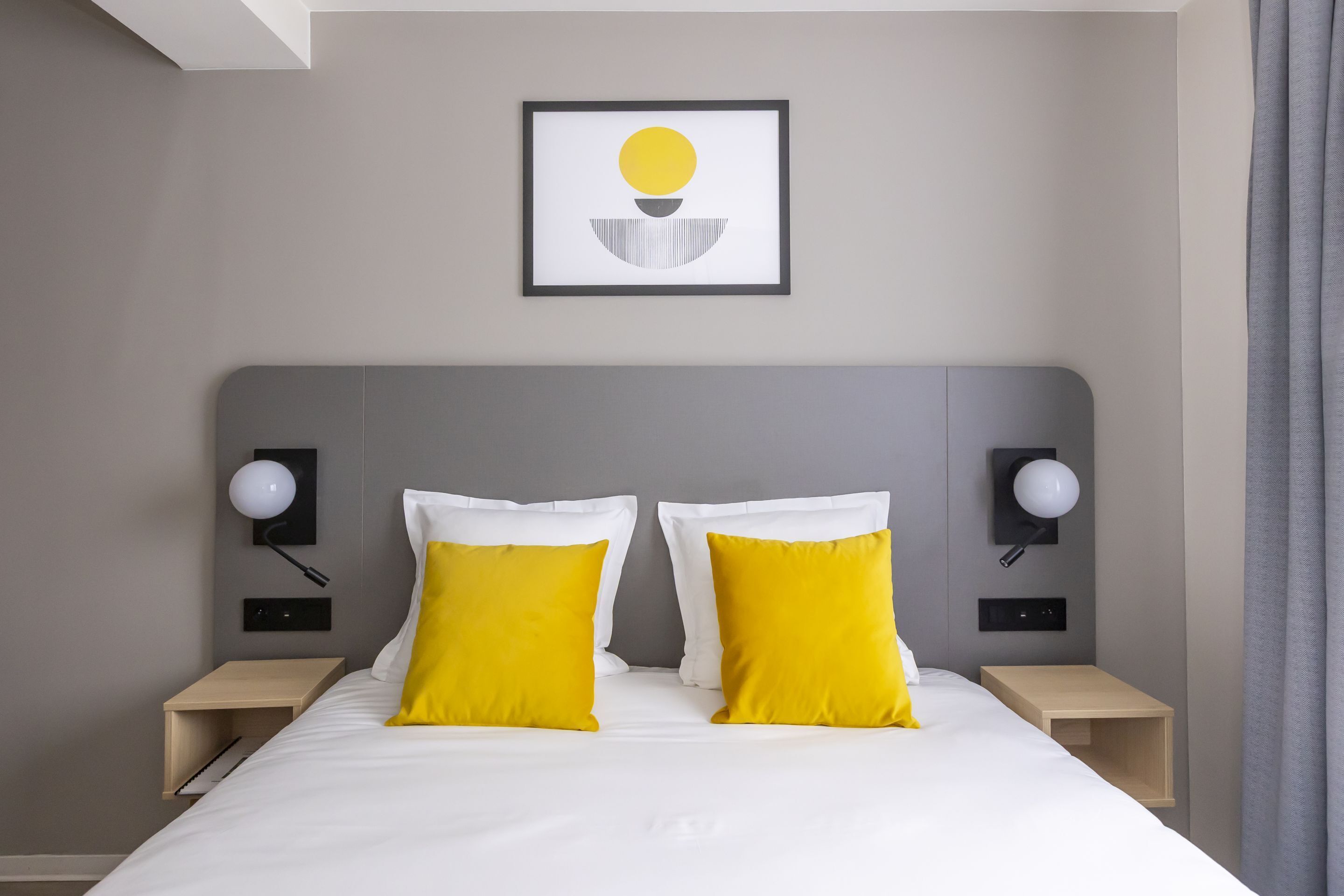 A hotel room with a bed, two bedside tables, and a wall-mounted picture.