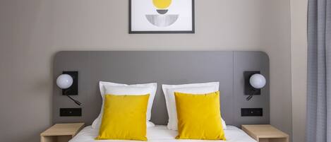 A hotel room with a bed, two bedside tables, and a wall-mounted picture.