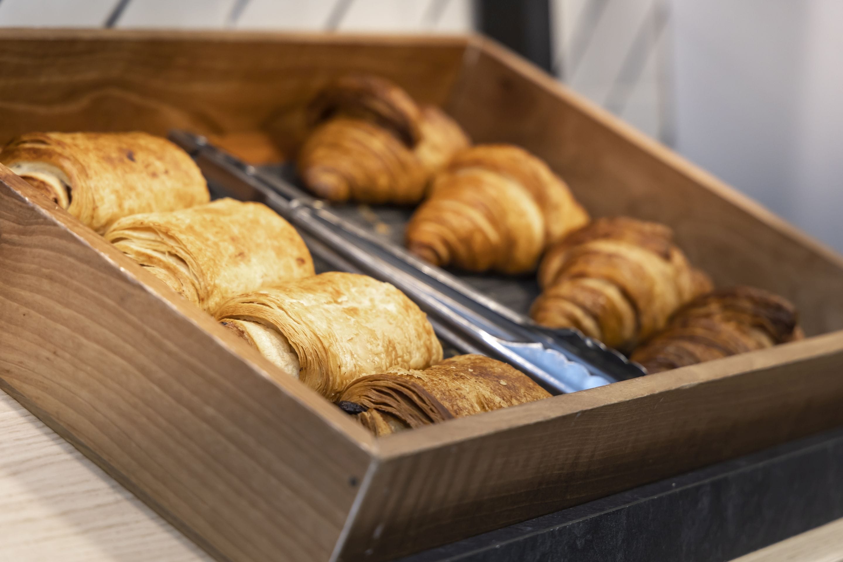 A wooden box containing several croissants.