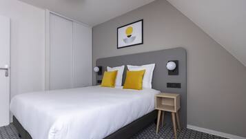 A modern bedroom with a large bed, a bedside table, and a wall-mounted light fixture.