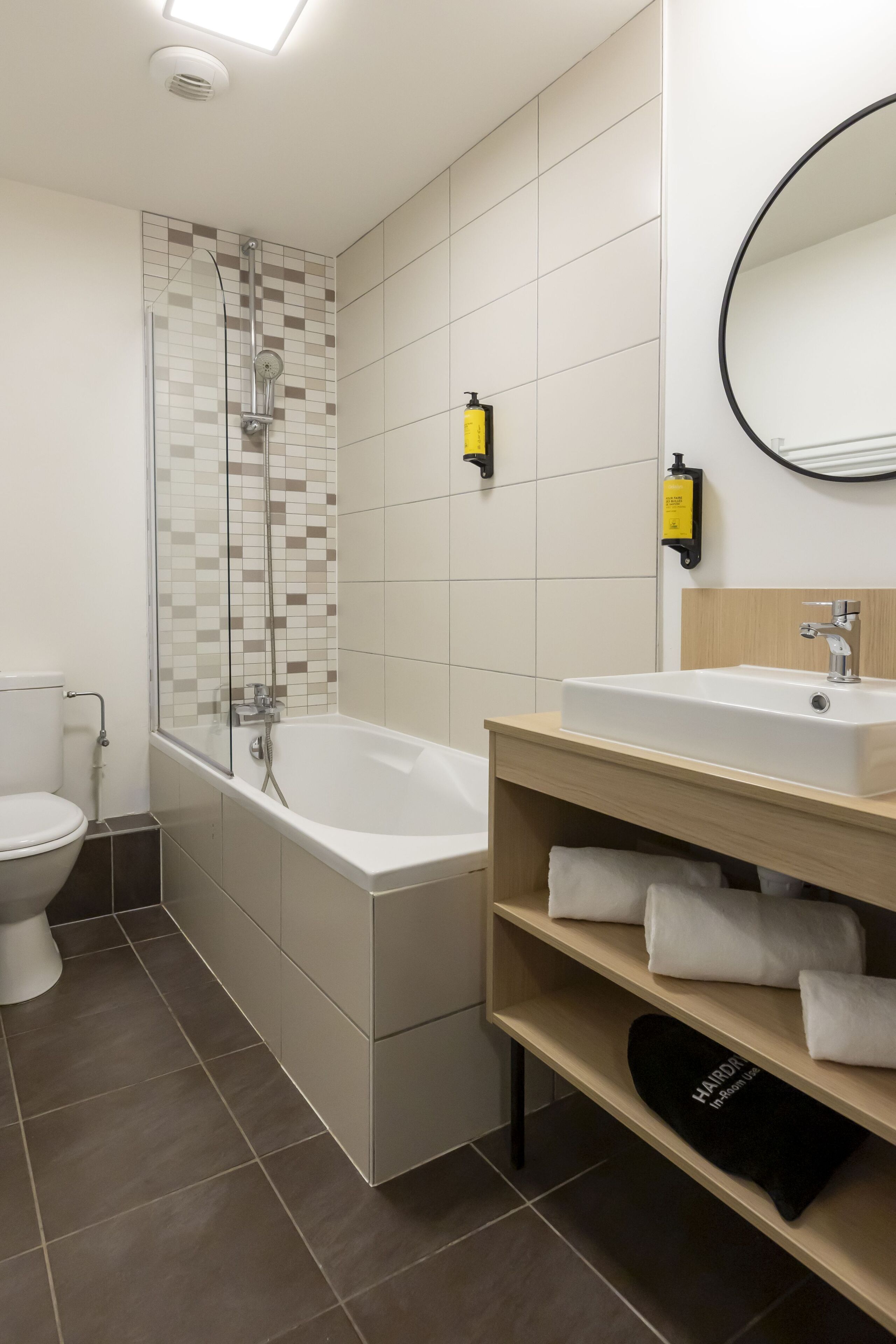 Ein modernes Badezimmer mit Dusche, Toilette und Waschbecken mit Spiegel darüber.