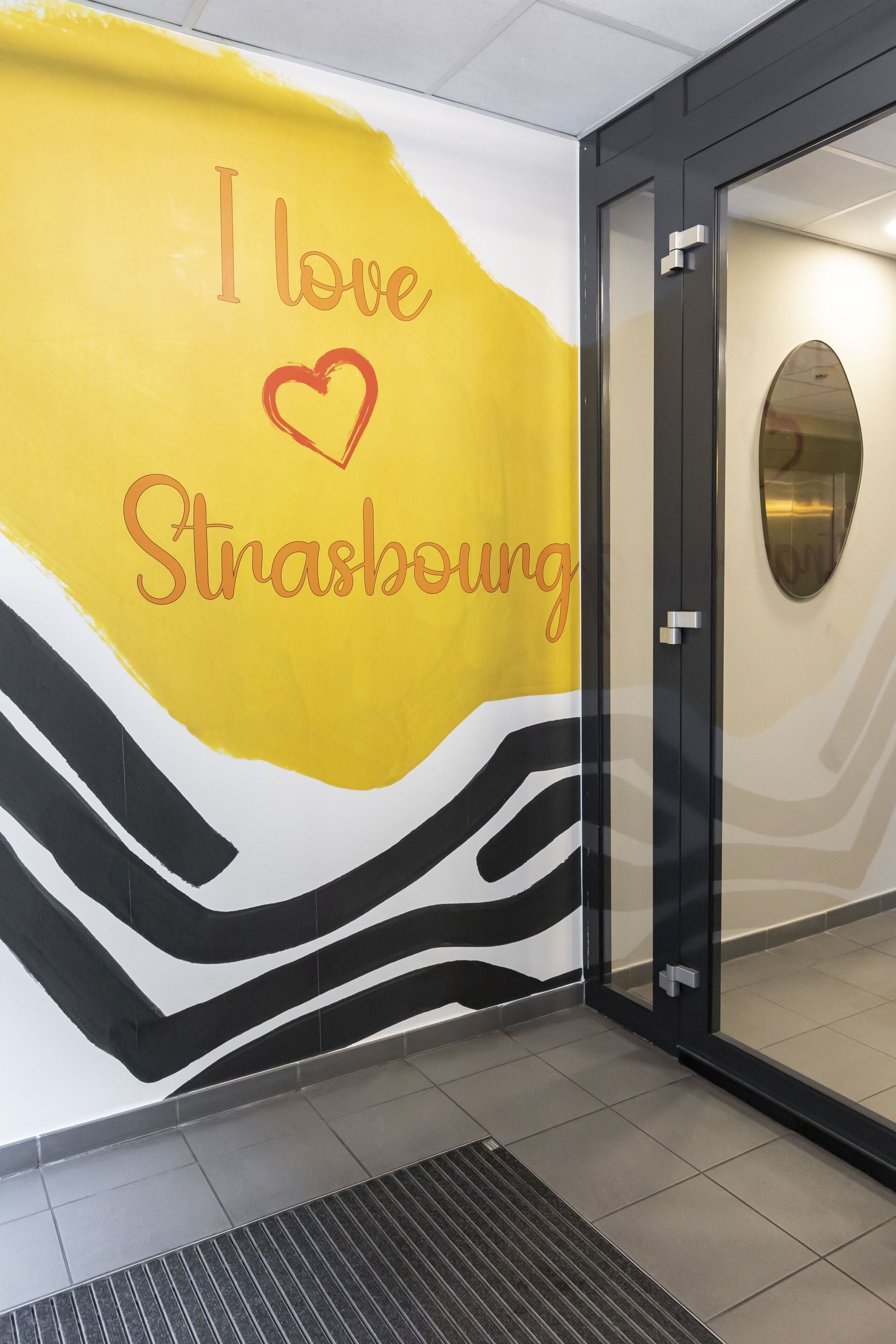 Un mur orné d’un motif abstrait jaune et noir, sur lequel on peut lire en rouge : « J’aime Strasbourg ».