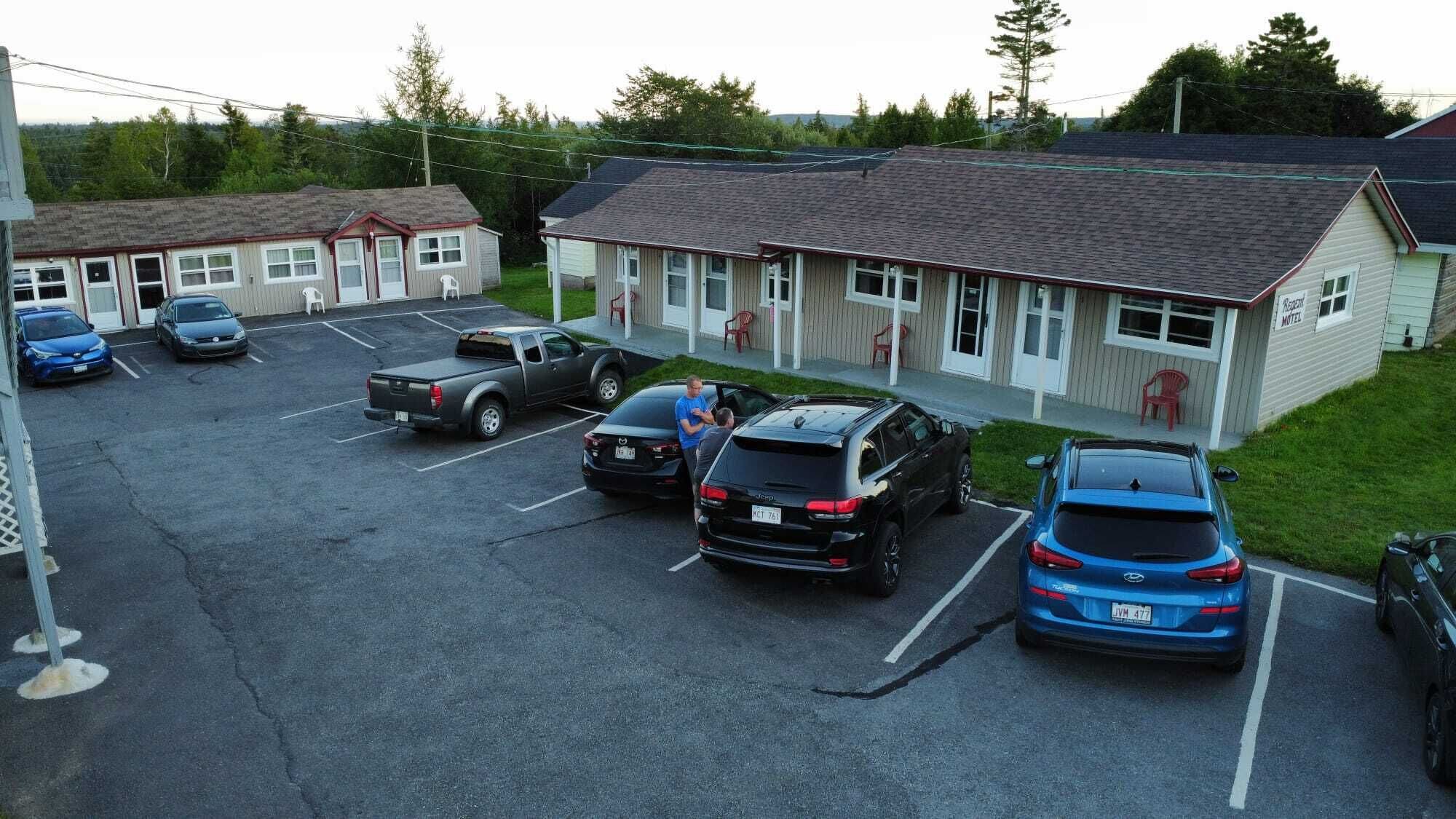Un motel con un estacionamiento que contiene varios autos.