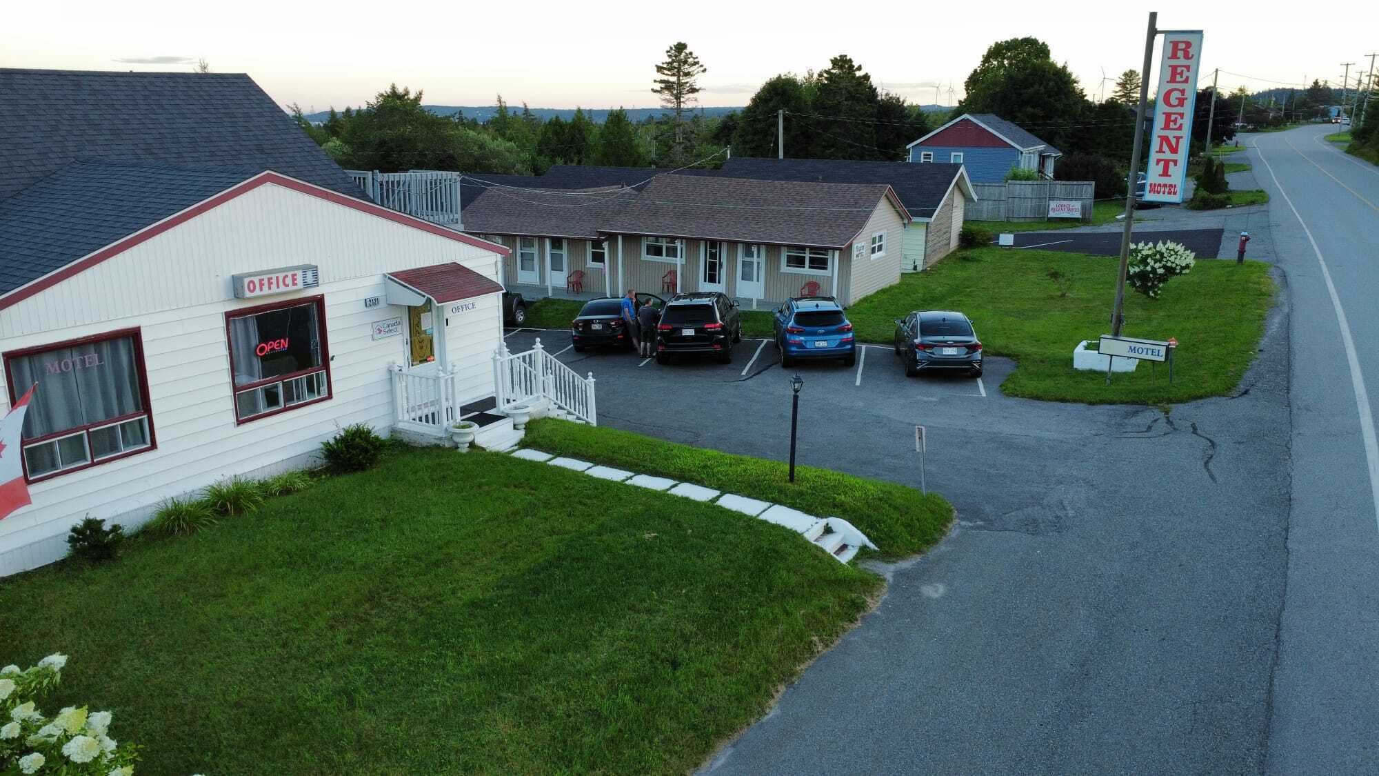 A motel with a white exterior, a small porch, and a parking lot with several cars.