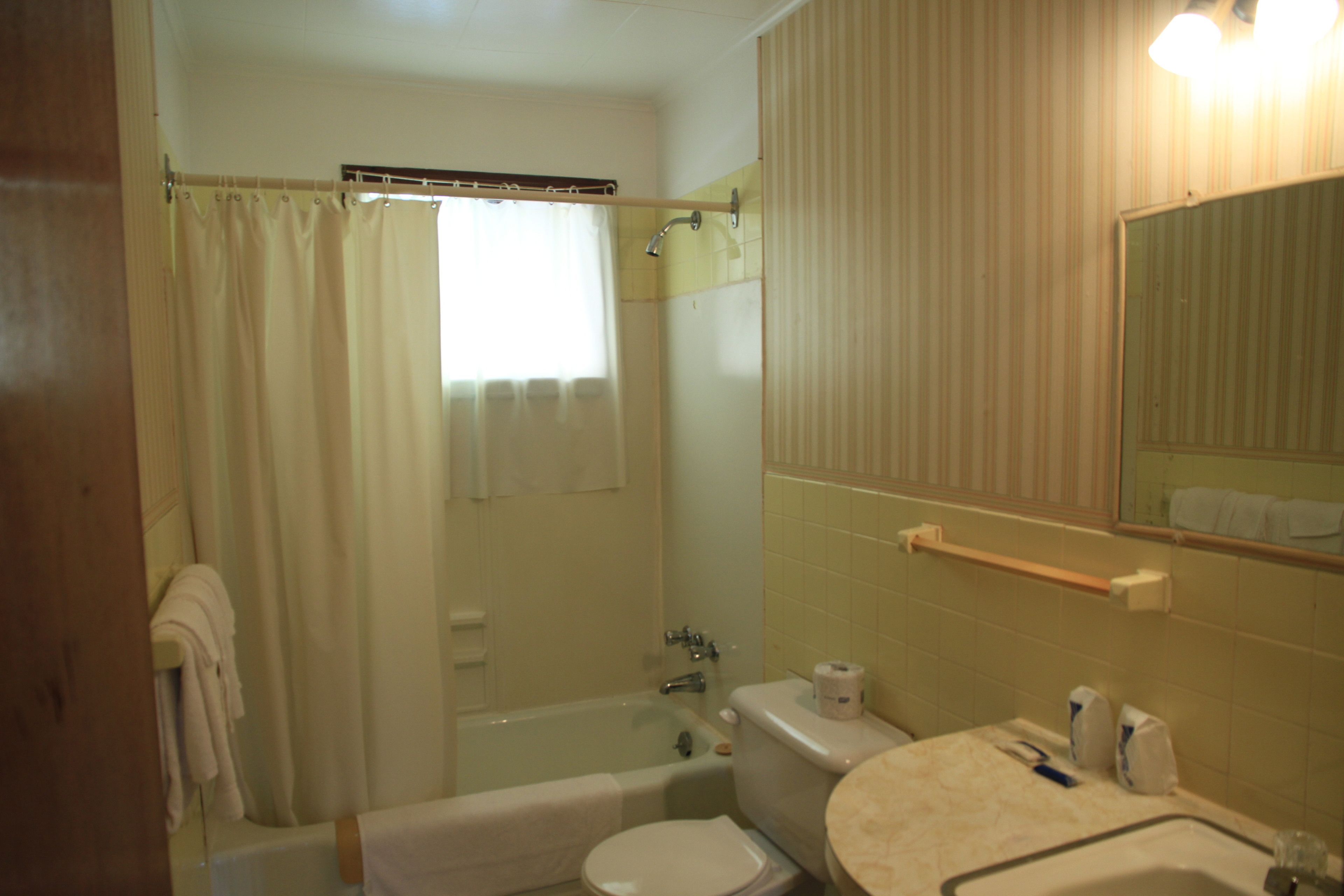 A bathroom with a bathtub, toilet, sink, and a mirror.