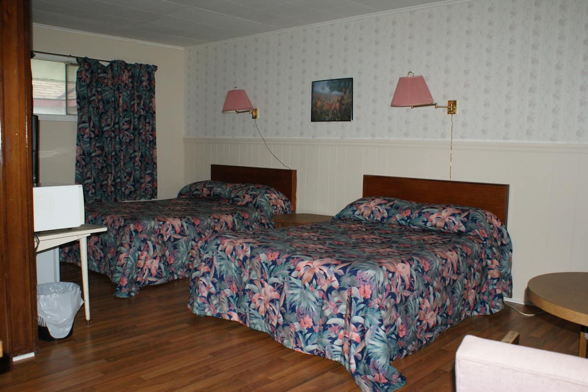 A room with two beds, a desk, and two lamps.