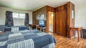 A room with two beds, a television, wooden panel walls, and a small table. - Regent Motel (Saint John)