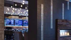 Een moderne hotel lobby met een receptie, zitplaatsen en een open haard.