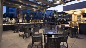 Een terras buiten met wicker meubels, een bar en een zwembad.