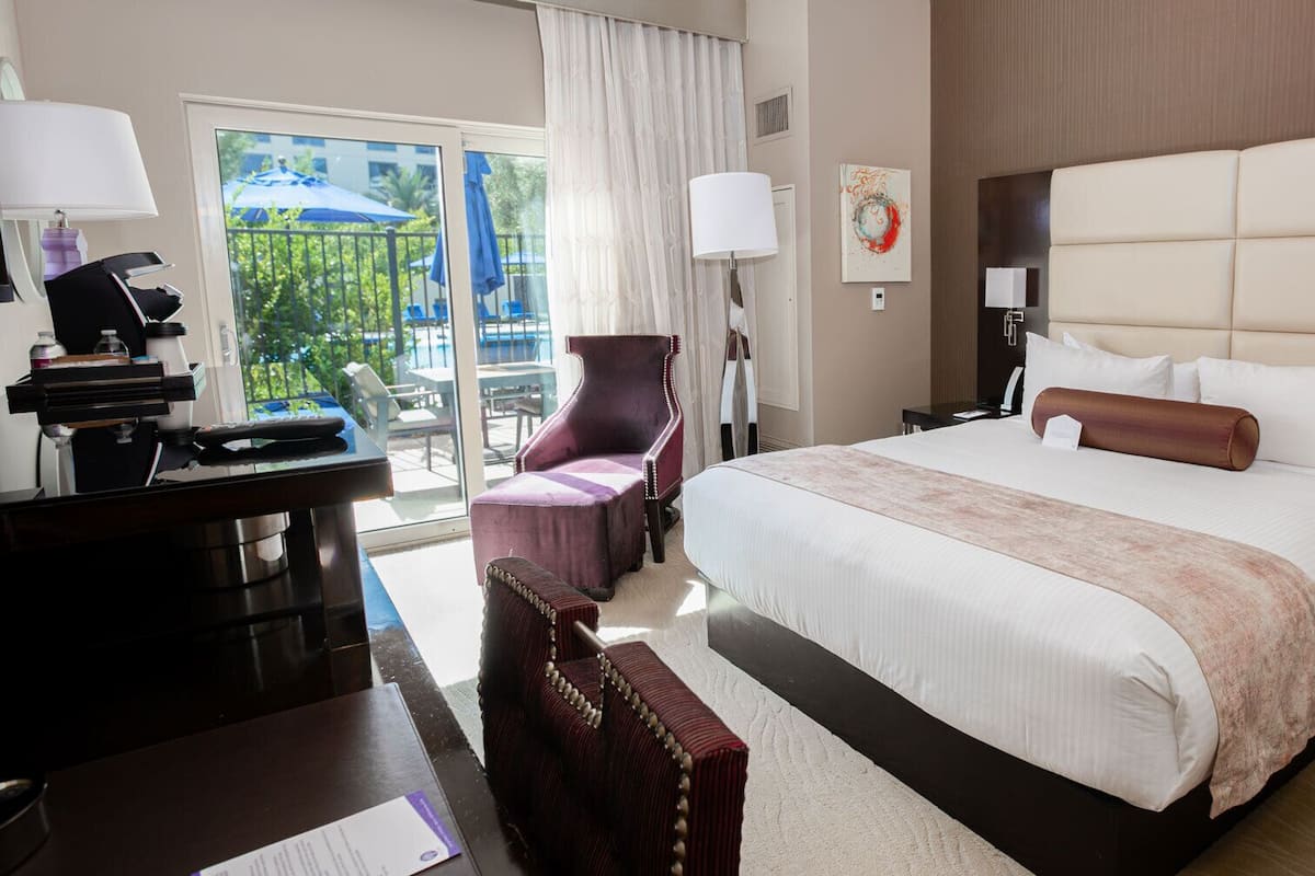 Une chambre d’hôtel avec un grand lit, un bureau équipé d’un ordinateur, une chaise et une vue sur l’ext érieur.