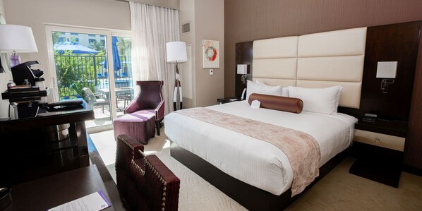 A hotel room with a large bed, a desk with a computer, a chair, and a view of the outdoors.