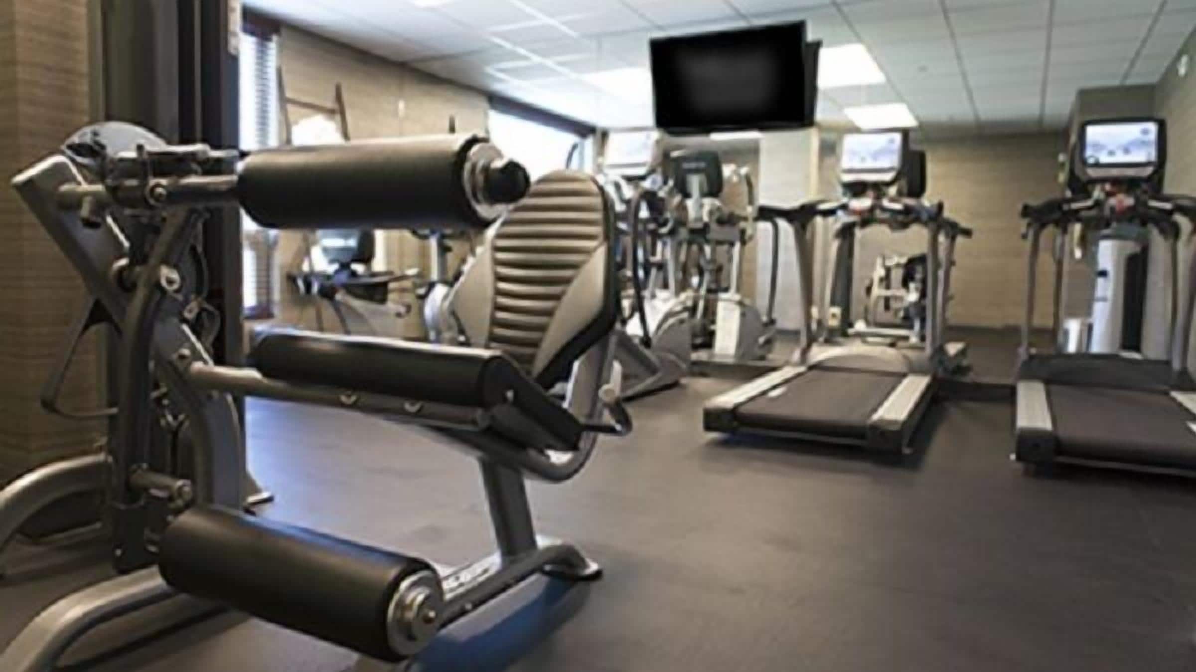 Un gimnasio con cintas de correr, elípticas y bicicletas estáticas.