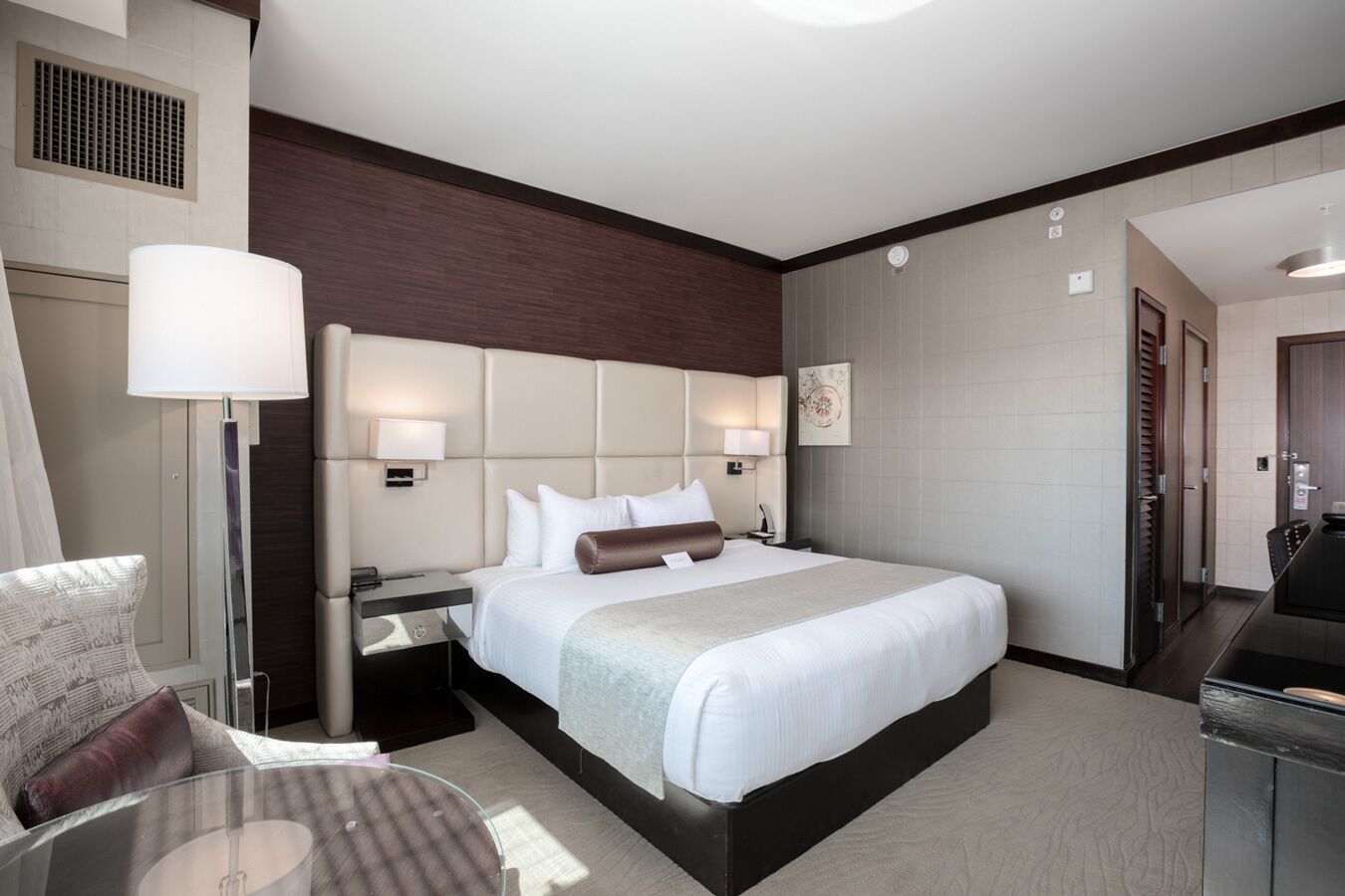 Une chambre d’hôtel avec un grand lit, un bureau, une chaise, une lampe et un tableau au mur.