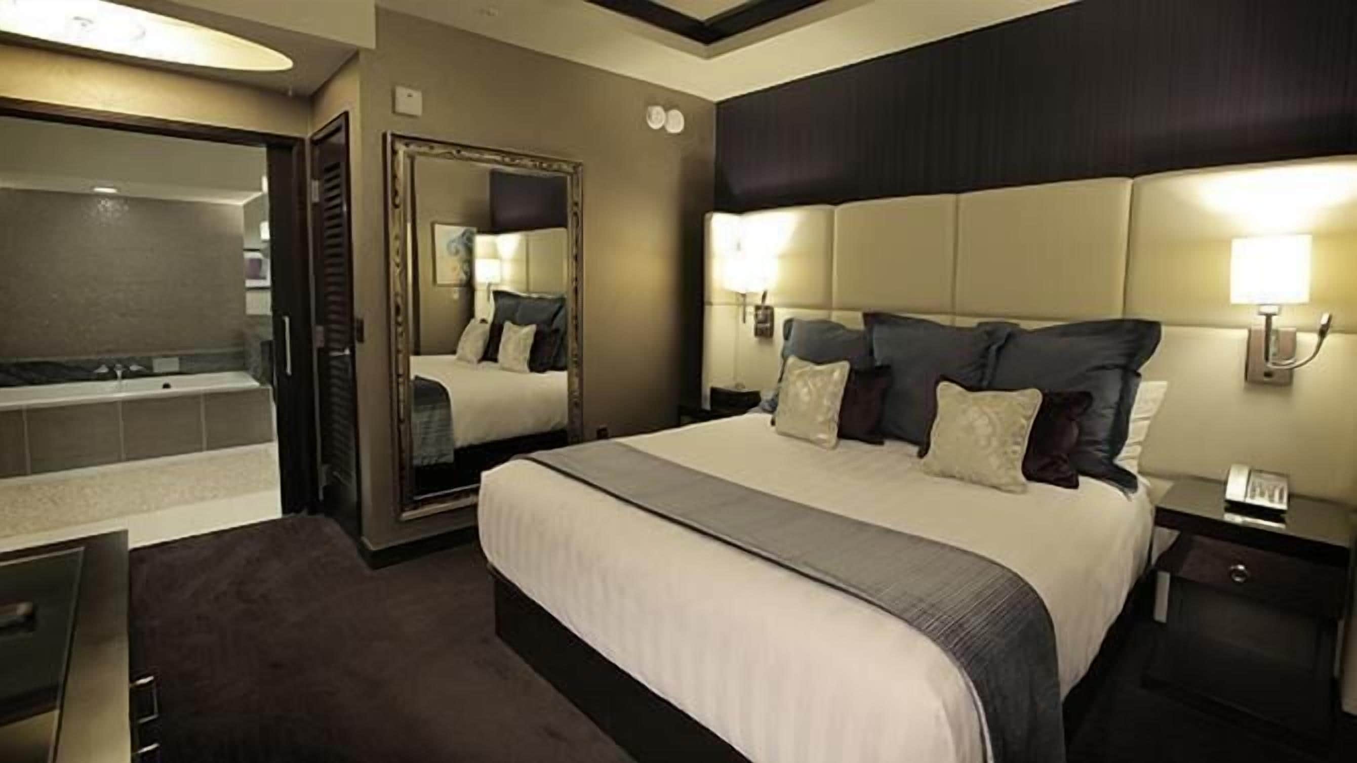 A hotel room with a large bed, a separate bathroom, and a desk.