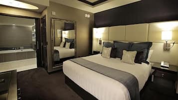 A hotel room with a large bed, a separate bathroom, and a desk.