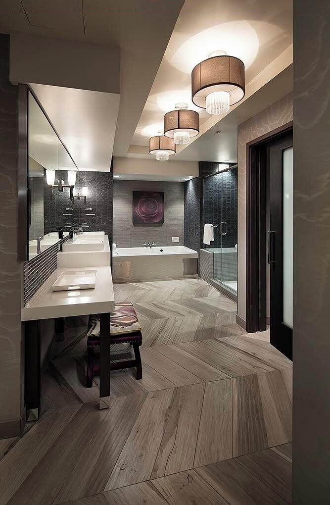 A modern bathroom with a large mirror, two sinks, a bathtub, and a shower.