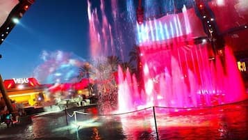 A water fountain with a red and blue light display, surrounded by a fence.