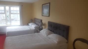 A hotel room with two beds, a window with curtains, a framed picture on the wall, and a chair.