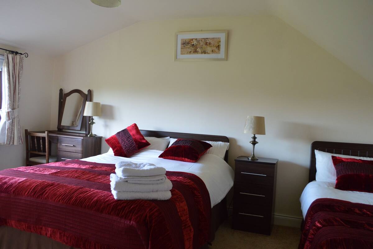 A hotel room with a large bed, two bedside tables, a mirror, and a painting on the wall.