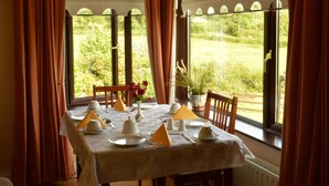 A dining table set for four with a view of a garden through large windows.
