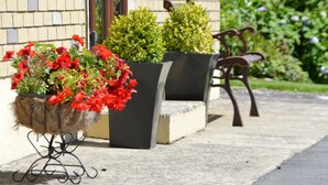 A building exterior with a brick wall, a concrete bench, and a metal chair.