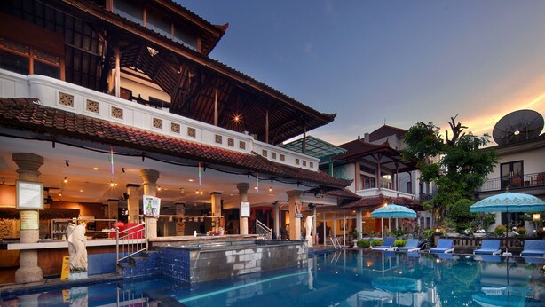 A hotel with a swimming pool, outdoor seating, and traditional architecture. - Legian Village Hotel (Legian)