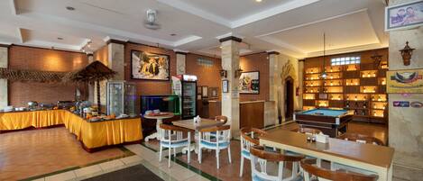 A dining area with a buffet, pool table, and seating.