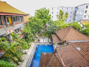 Relax by the serene pool surrounded by lush greenery and traditional architecture.