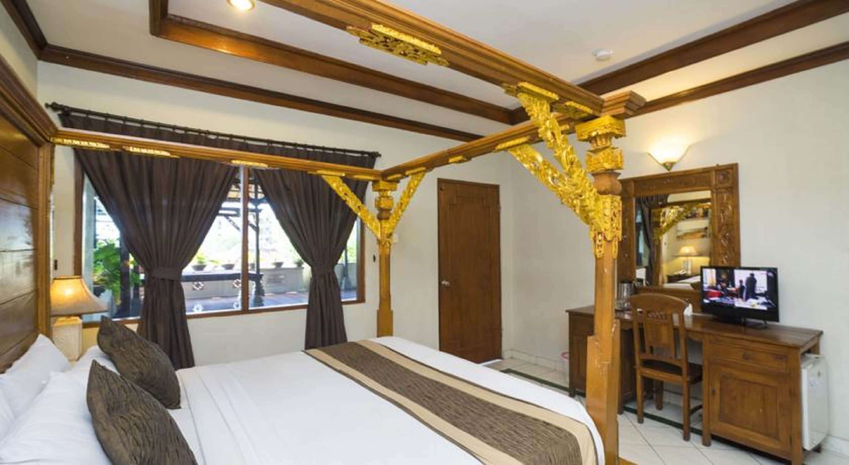 A bedroom with a four-poster bed, a wooden desk, a television, and a window with curtains.