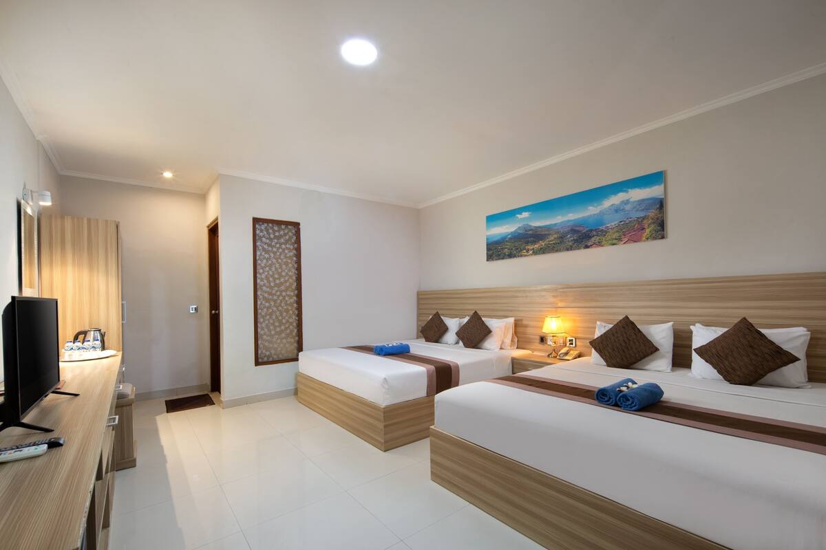 A hotel room with two beds, a TV, and a painting on the wall.