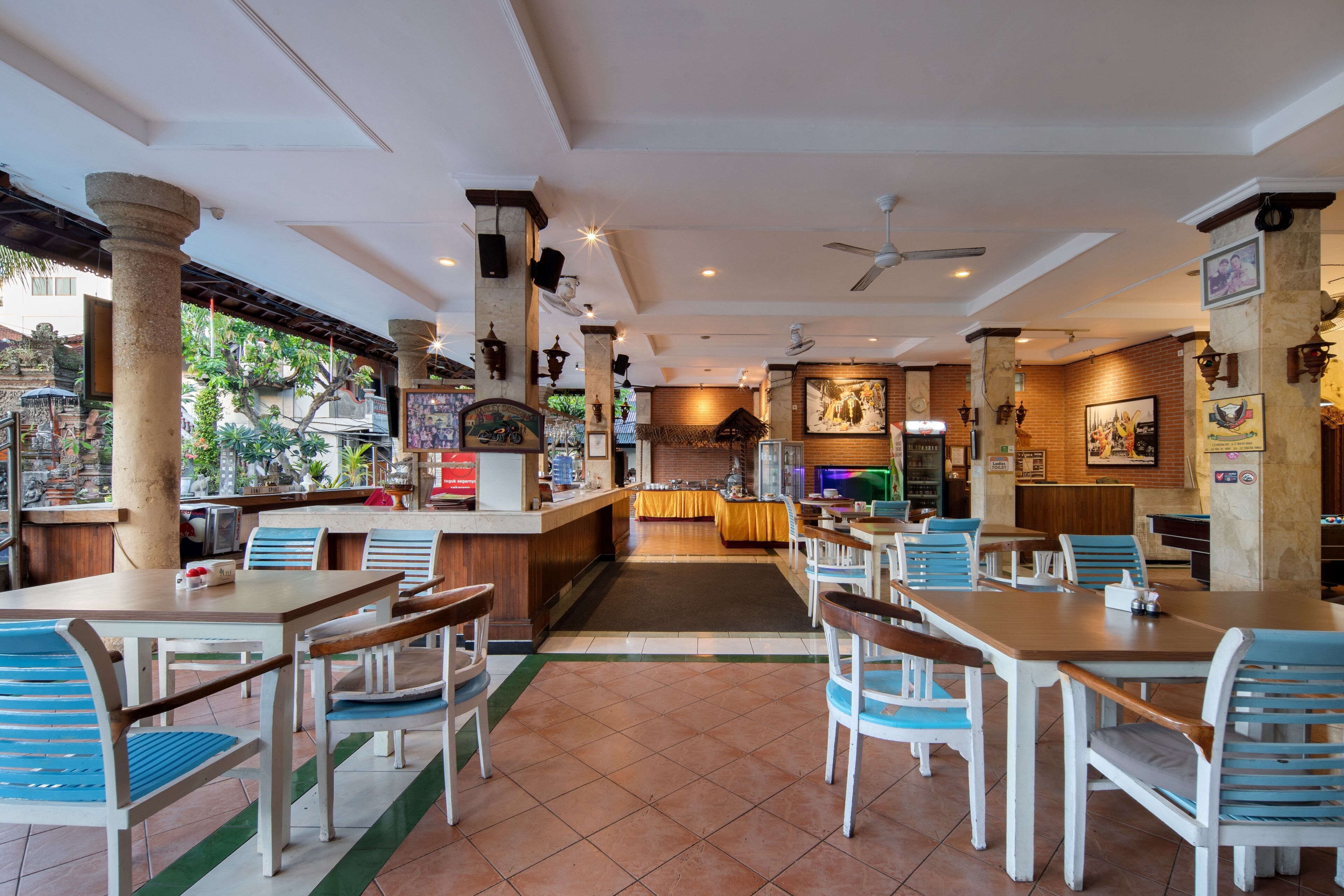 A restaurant with a bar area, multiple tables and chairs, and a view of the outside.