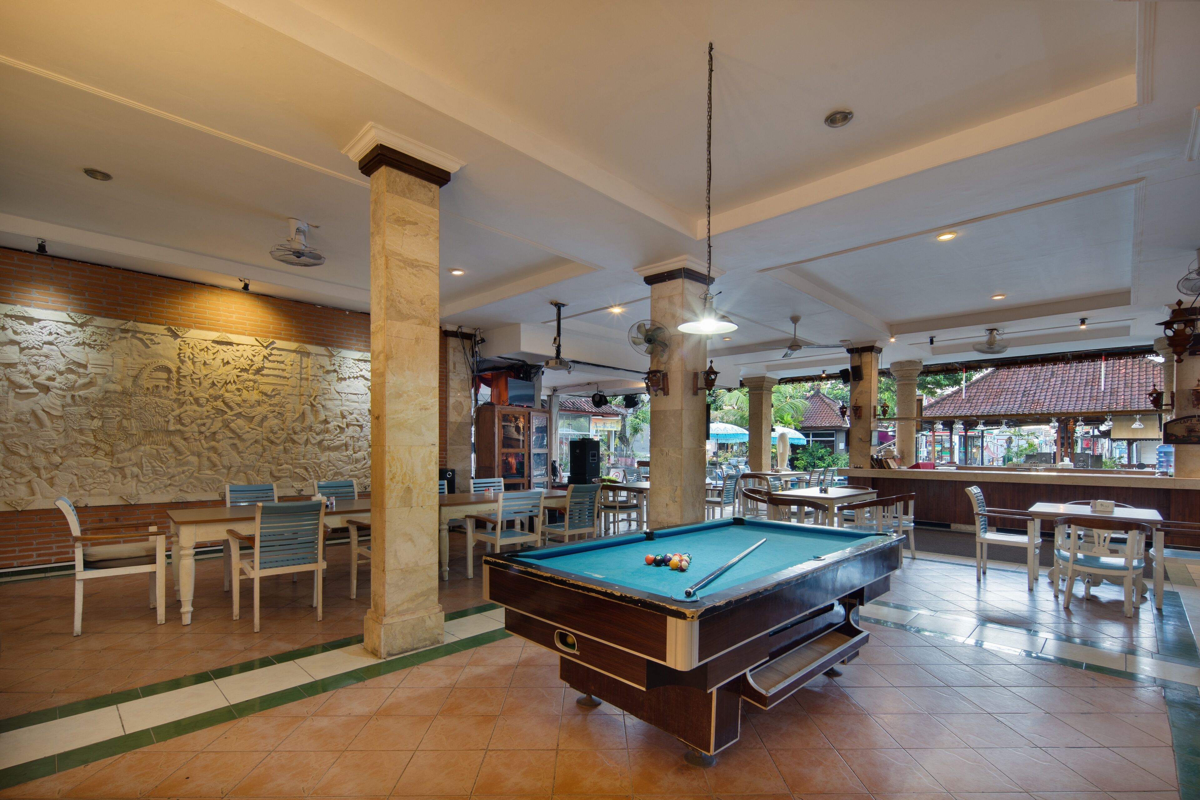 A pool table in a spacious indoor area with a stone wall and wooden benches.