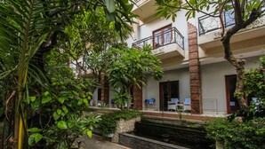 A courtyard with a small water feature, potted plants, and a building with balconies. - Legian Village Hotel (Legian)