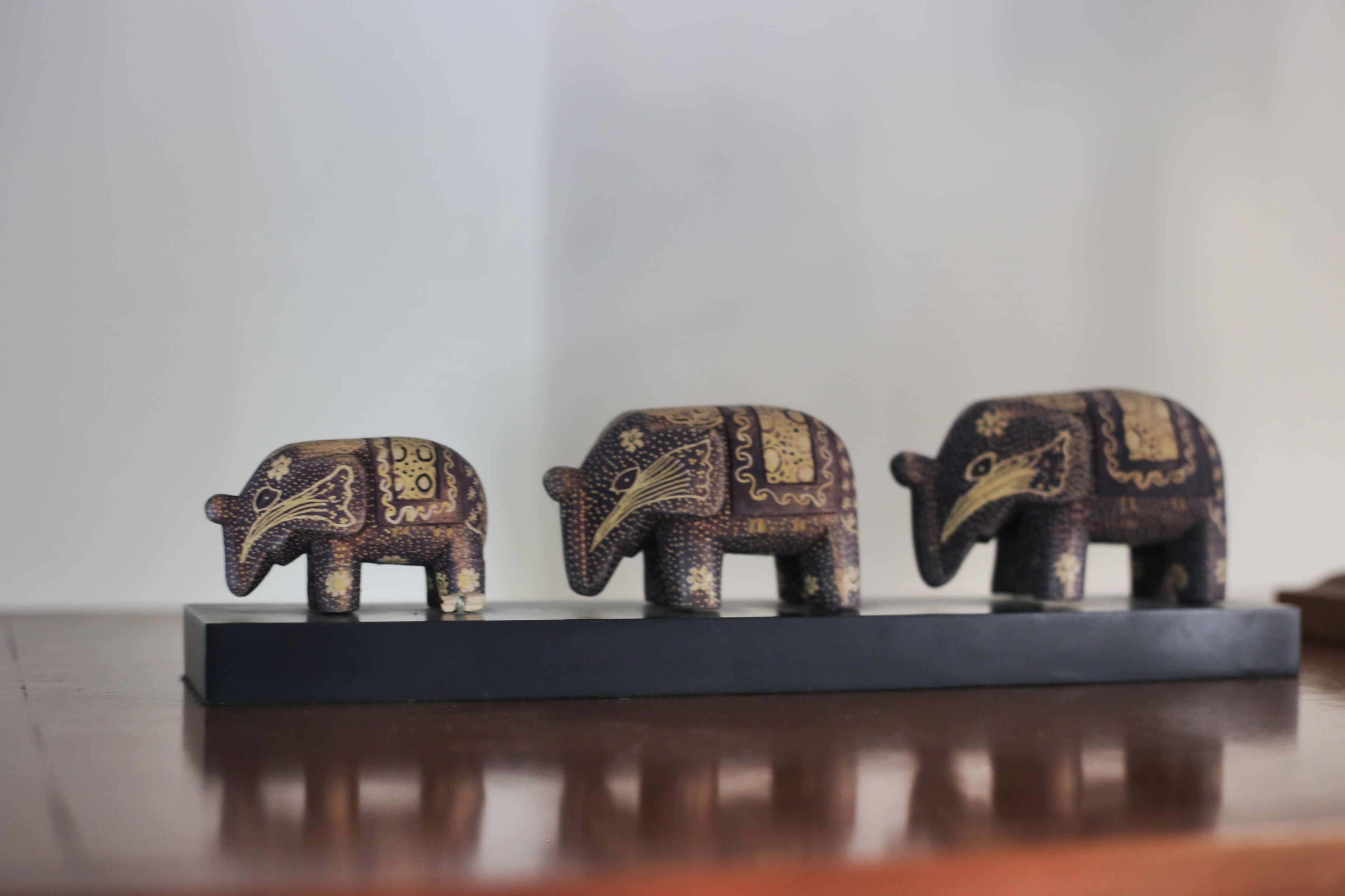 Three elephant-shaped sculptures on a dark rectangular base.