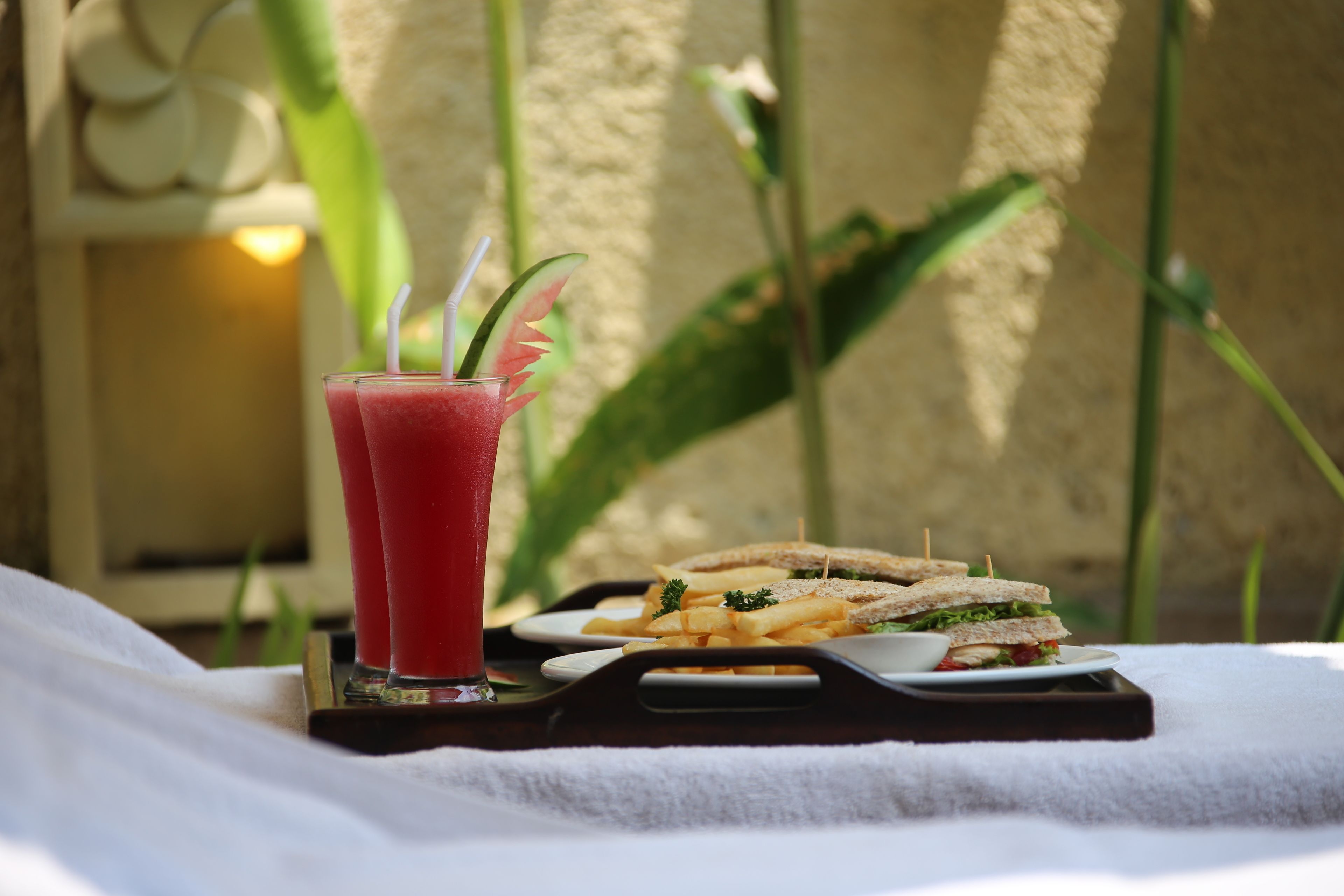 A tray with a sandwich and a glass of red drink on a white towel.