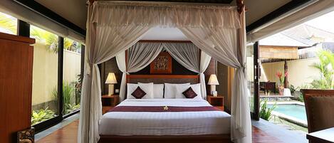 A four-poster canopy bed with a wooden headboard, white linens, and decorative pillows.