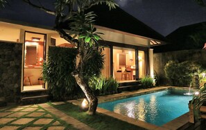 A modern house with a swimming pool, surrounded by greenery and a stone wall. - The Sanyas Suite (Seminyak)