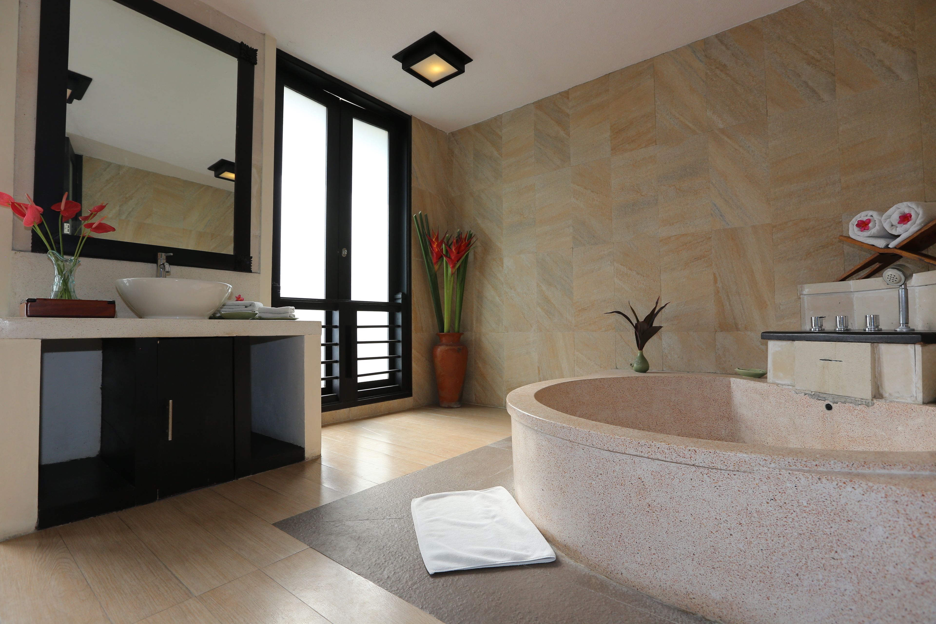 A modern bathroom with a freestanding bathtub, a large mirror, and a vanity with a sink.