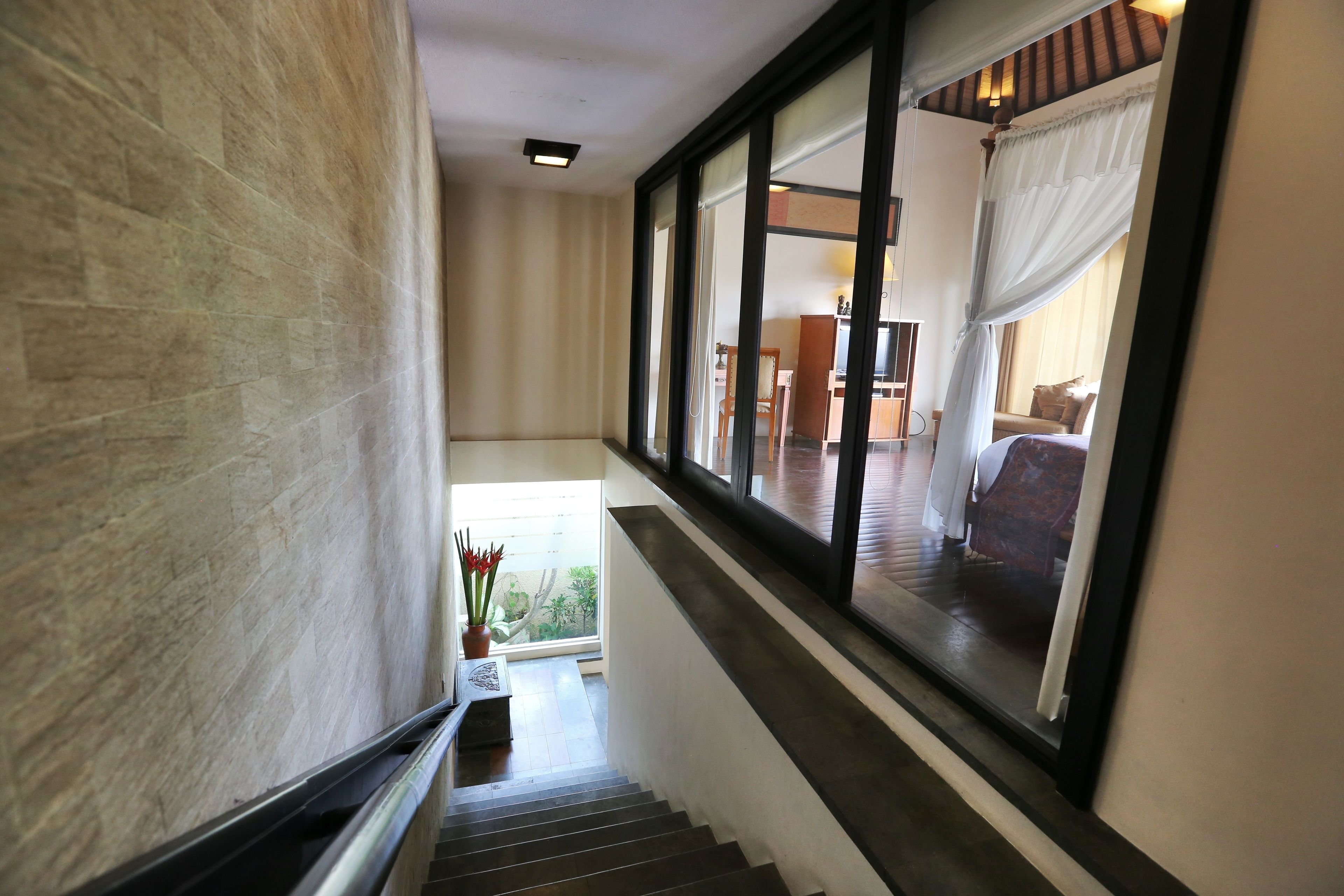 A staircase with a view of a room through a large window.