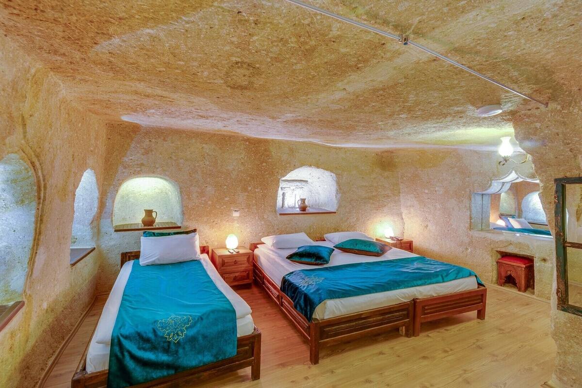 Ein rustikaler Raum mit zwei Holzbetten, einem kleinen Tisch und einem Spiegel.