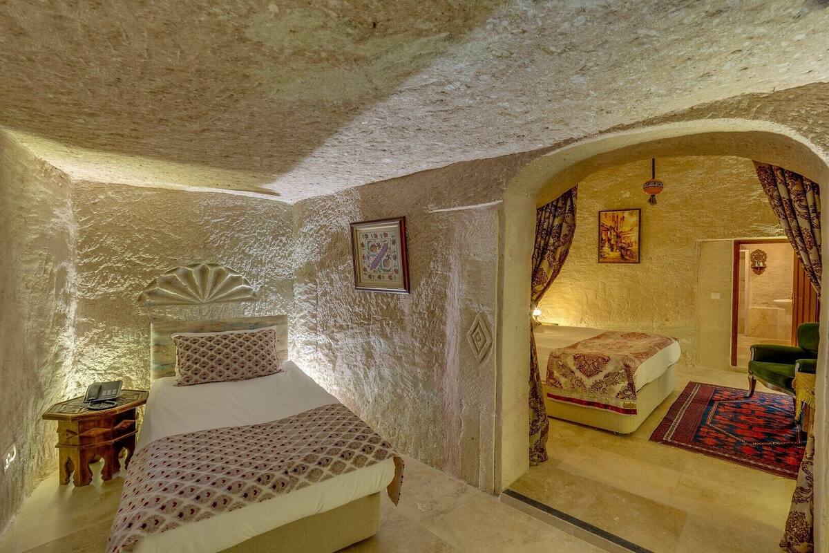 Ein Zimmer mit einem Bett, einem Nachttisch, einem Stuhl und einer Tür zu einem anderen Raum.