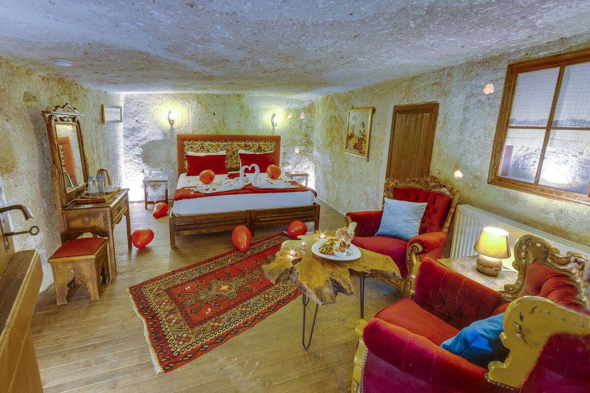 Ein Zimmer mit einem großen Bett, einem roten Sofa, einem Holztisch und einem roten Teppich.