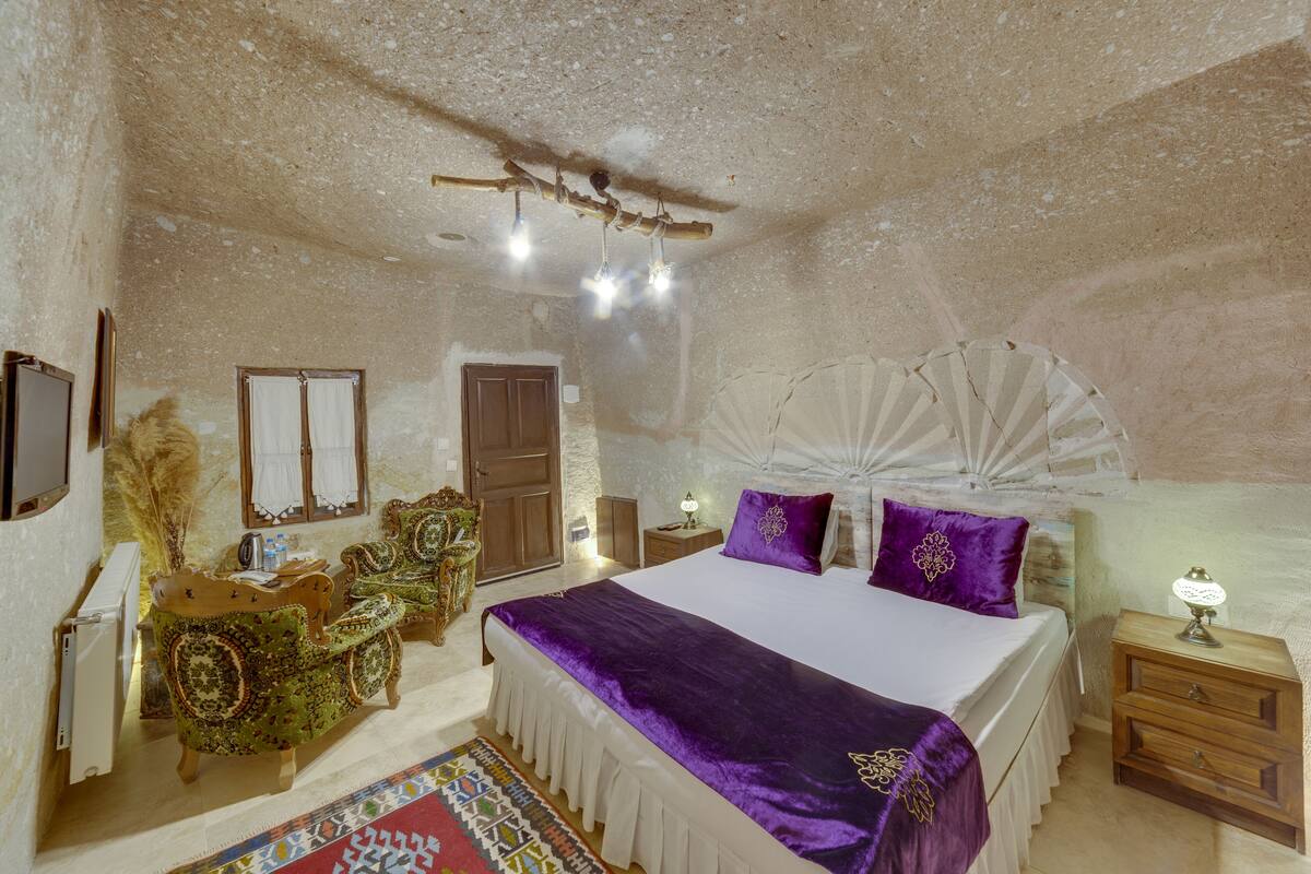 Ein Schlafzimmer mit einem großen Bett, einem Nachttisch aus Holz, einem Sessel und einem kleinen Tisch.