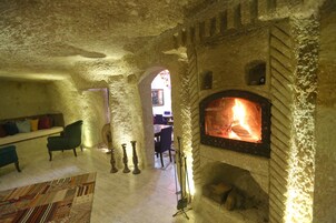 Una habitación con paredes de piedra, chimenea, sofá y alfombra estampada.